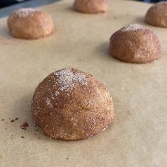 doughnuts sitting on top of a baking sheet covered in powdered sugar, ready to be baked