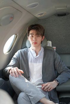 a young man sitting in the seat of an airplane with his hand on his hip