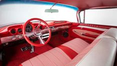 the interior of an old car with red and white leather seats, steering wheel and dash board