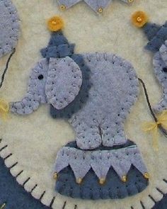 an elephant made out of knitted material on top of a white tablecloth with yellow and blue decorations