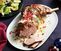 a large piece of meat sitting on top of a white plate next to a bowl of vegetables