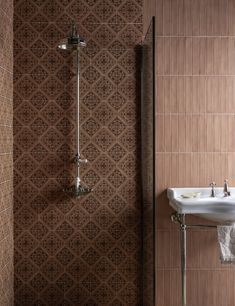 a bathroom with a sink, mirror and shower head in brown tile pattern on the wall