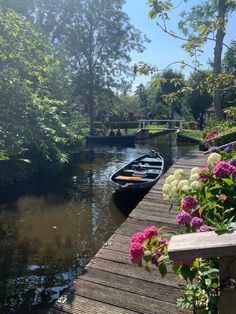 a boat is docked at the end of a wooden dock with flowers in front of it