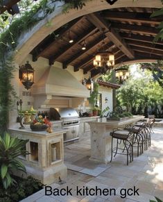 an outdoor kitchen with grill and seating under a pergolated roof, surrounded by greenery