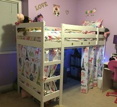 a bedroom with bunk beds and curtains on the bottom floor, in front of a window