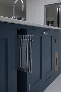 a kitchen with blue cabinets and white countertops has a striped towel hanging from the door