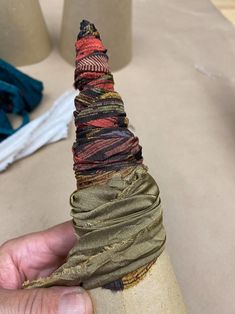 a hand holding a piece of fabric wrapped around a cone