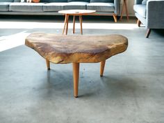 a wooden table sitting on top of a cement floor next to a couch and coffee table