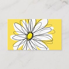 a yellow and white business card with a large flower on the front, sitting on a marble surface