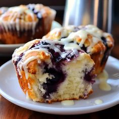 blueberry muffins with icing on a white plate