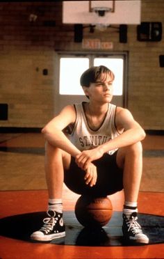 a young man sitting on top of a basketball court