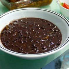 there is a bowl of beans on the table next to some other bowls and food