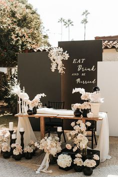 a table topped with flowers and candles next to a sign that says eat drink and be married