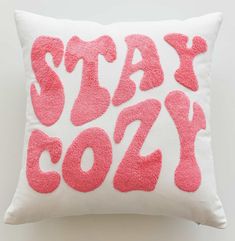 a pink and white pillow with the words stay cozy printed on it in red ink