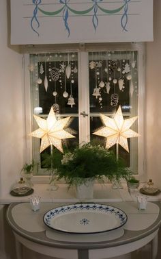 a white table topped with a potted plant next to a window covered in lights