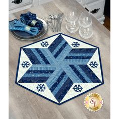 a blue and white quilted table topper next to silverware on a wooden table