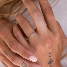 a woman's hand with a diamond ring on her left wrist and tattoos on the other hand