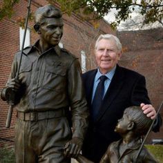 a man standing next to a statue of a boy holding a baseball bat