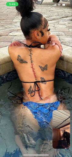 a woman with tattoos on her back sitting in a pool