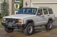 a white jeep parked in front of a garage