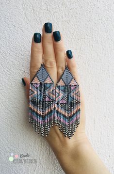 a woman's hand holding two pairs of beaded earrings on top of her fingers