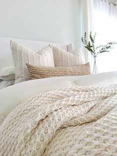 a white bed topped with pillows and blankets