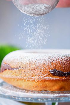 a person sprinkling sugar on a cake