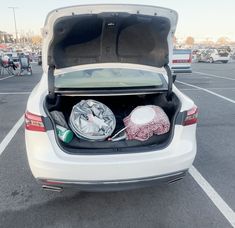 the back end of a white car with its trunk open and various items in it