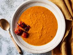 a white bowl filled with carrot soup and garnished with dried tomatoes on top