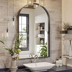 a bathroom sink sitting under a mirror next to a bath tub and window with potted plants on it