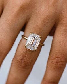 a woman's hand with a ring on it and an emerald stone in the middle