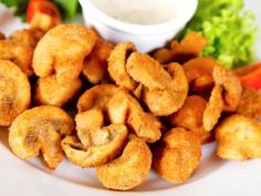 some fried food on a white plate with lettuce and carrots next to it