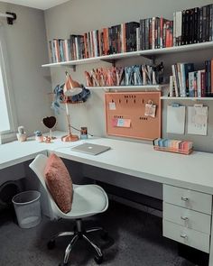 a white desk topped with a laptop computer next to a book shelf filled with books