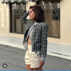 a woman standing in front of a store with her back to the camera, wearing a jacket and shorts