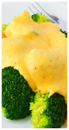 broccoli florets covered in cheese sauce on a plate with a fork