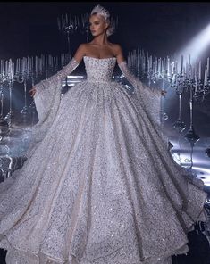 a woman in a white gown standing on a stage with lights behind her and an elaborate headpiece