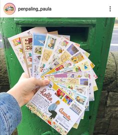 a person is holding up some stamps in front of a green mailbox with the words peppaling - paula on it