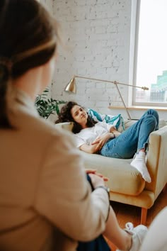 a woman laying on a couch with her eyes closed and one hand up to the side