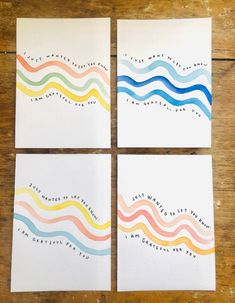 four cards with colorful waves on them sitting on top of a wooden table next to each other