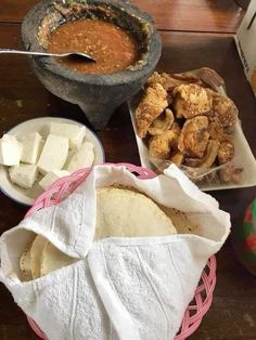 some food is sitting on a table with bowls and spoons next to each other