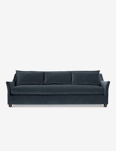 a dark blue couch with three pillows on the back and one arm folded over it