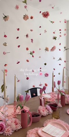 a dining room table with pink flowers and candles on the wall above it is decorated with paper flowers