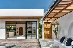 an outdoor living area with white walls and wooden ceilinging, surrounded by potted plants