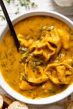 a bowl of soup with tortilla shells in it and bread on the side