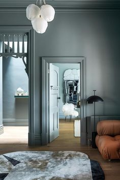 a living room filled with furniture and a white light hanging from the ceiling above it