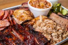 a tray with ribs, meat and sides on it