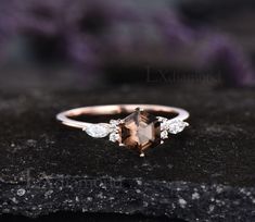 an engagement ring with a brown and white stone surrounded by diamonds on top of a rock