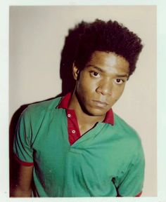 a young man in a green shirt posing for a photo with his hair pulled back