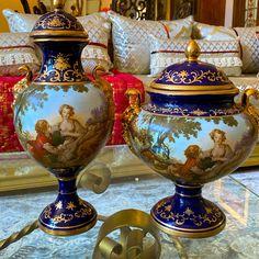 two blue and gold vases sitting on top of a glass table next to each other