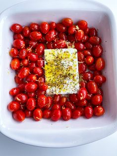 a square white bowl filled with tomatoes and seasoning